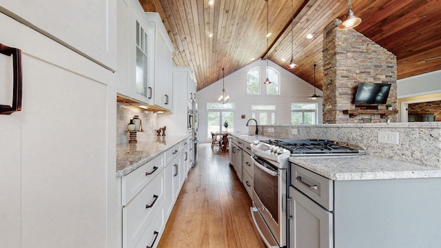 kitchen featuring pendant lighting, white cabinets, light hardwood / wood-style floors, gas range, and tasteful backsplash