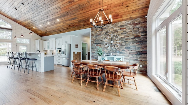 dining space with light hardwood / wood-style flooring, an inviting chandelier, high vaulted ceiling, and wooden ceiling