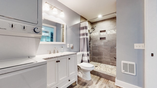 bathroom with vanity, stacked washer / dryer, a shower with curtain, toilet, and hardwood / wood-style flooring