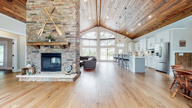 living room featuring wooden ceiling, light hardwood / wood-style floors, high vaulted ceiling, and a fireplace