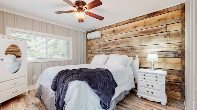 bedroom featuring wooden walls, a wall unit AC, ceiling fan, and light wood-type flooring