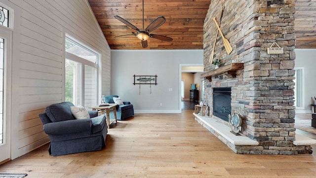 living room with a stone fireplace, light hardwood / wood-style floors, ceiling fan, and high vaulted ceiling