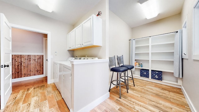 laundry room with light hardwood / wood-style flooring, cabinets, and washing machine and dryer