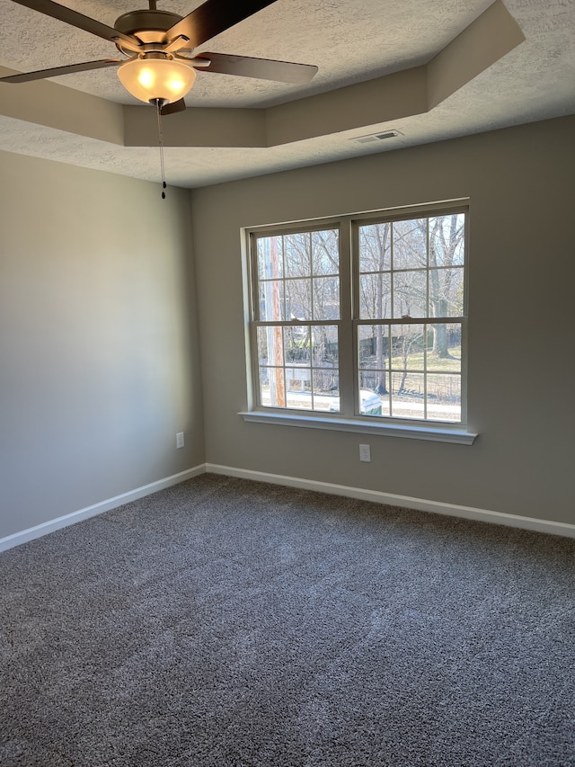 spare room featuring carpet, a textured ceiling, a tray ceiling, and ceiling fan