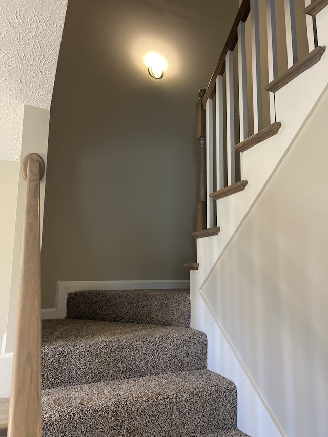 stairway featuring a textured ceiling