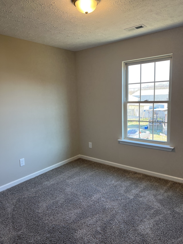 carpeted empty room with a textured ceiling