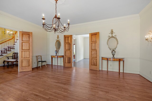 spare room with crown molding, a notable chandelier, and dark wood-type flooring