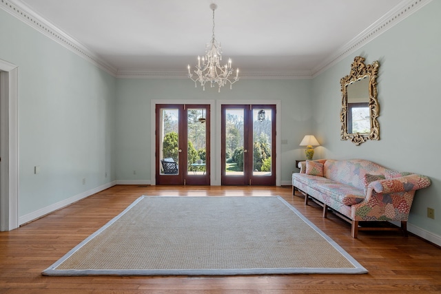 living area featuring light hardwood / wood-style flooring, ornamental molding, a chandelier, and french doors