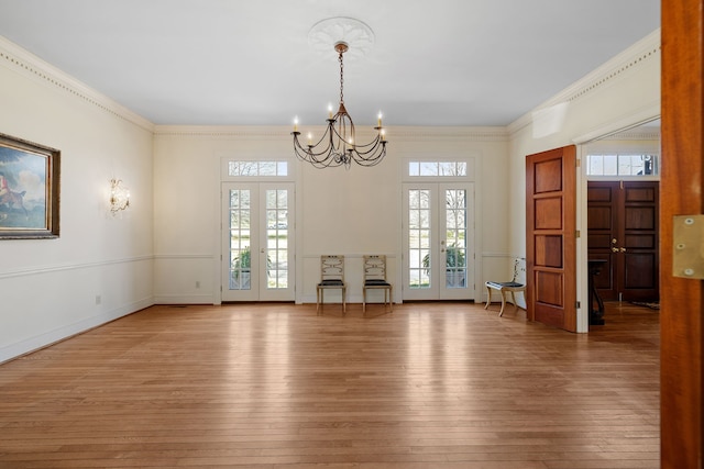 empty room with a chandelier, light hardwood / wood-style floors, and crown molding