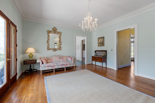 sitting room with dark hardwood / wood-style flooring, ornamental molding, and an inviting chandelier