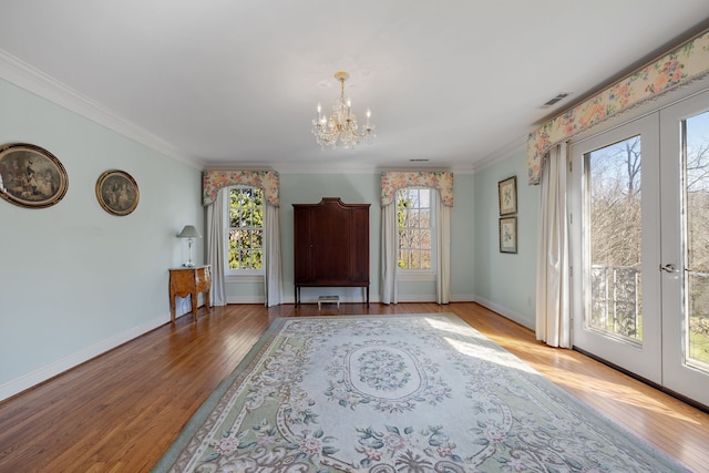 interior space with a chandelier, a healthy amount of sunlight, ornamental molding, and light hardwood / wood-style floors