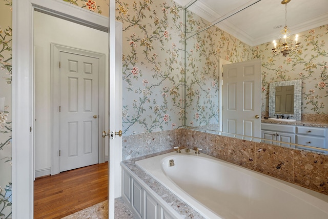 bathroom with wood-type flooring, a tub, a notable chandelier, vanity, and crown molding