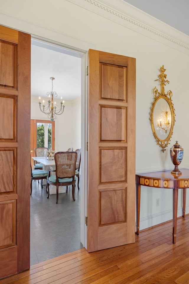 hall with a chandelier, light hardwood / wood-style flooring, and crown molding