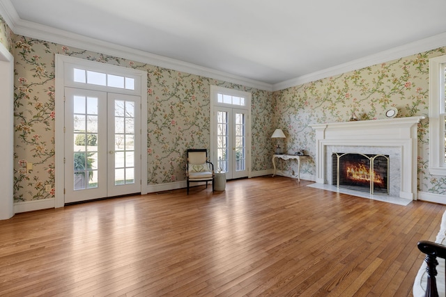 unfurnished living room featuring plenty of natural light, crown molding, french doors, and light hardwood / wood-style flooring