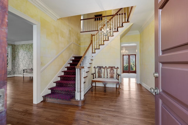 stairway with an inviting chandelier, hardwood / wood-style flooring, and ornamental molding