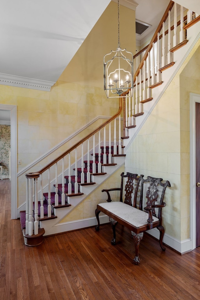 stairway featuring a notable chandelier, crown molding, and hardwood / wood-style floors