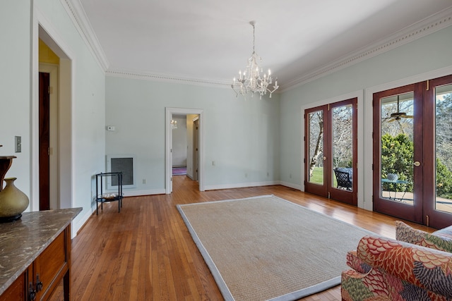 interior space featuring french doors, ornamental molding, a chandelier, and light wood-type flooring