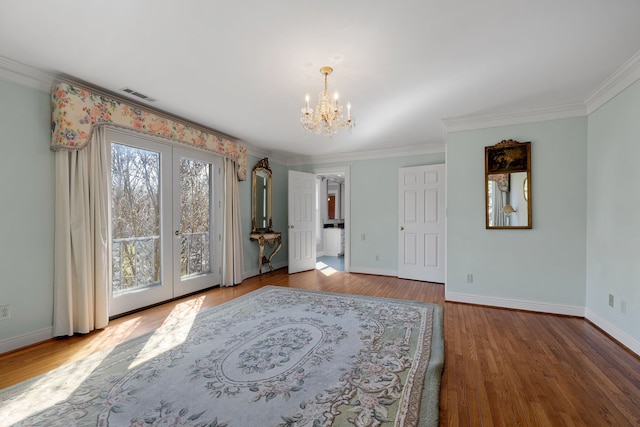 unfurnished room with an inviting chandelier, light wood-type flooring, ornamental molding, and french doors