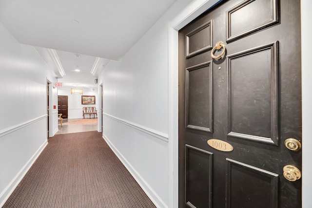 hallway with dark carpet and ornamental molding