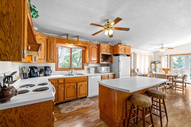 kitchen with a center island, sink, dark hardwood / wood-style floors, white appliances, and a kitchen bar