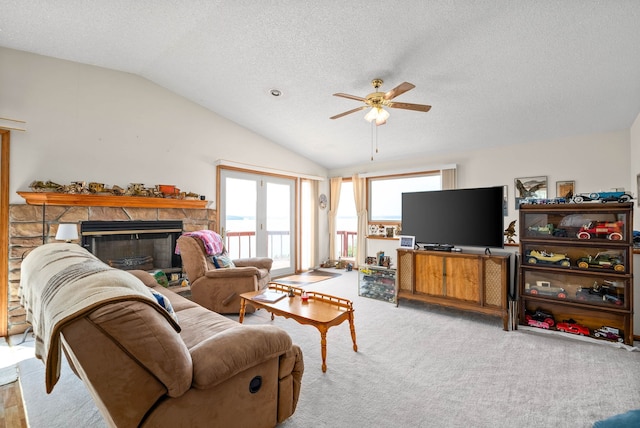 living room featuring lofted ceiling, ceiling fan, a fireplace, a textured ceiling, and light colored carpet