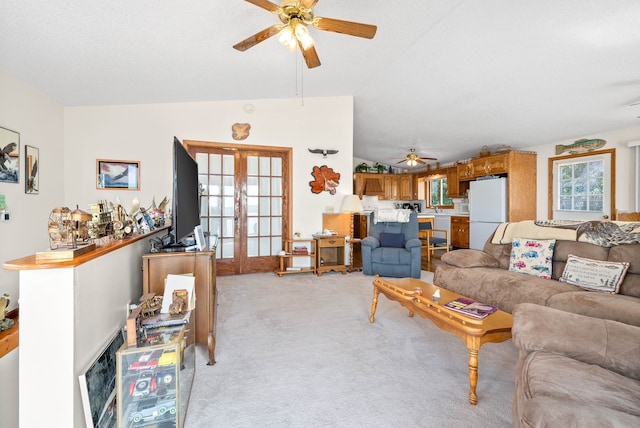 carpeted living room with plenty of natural light, vaulted ceiling, ceiling fan, and french doors