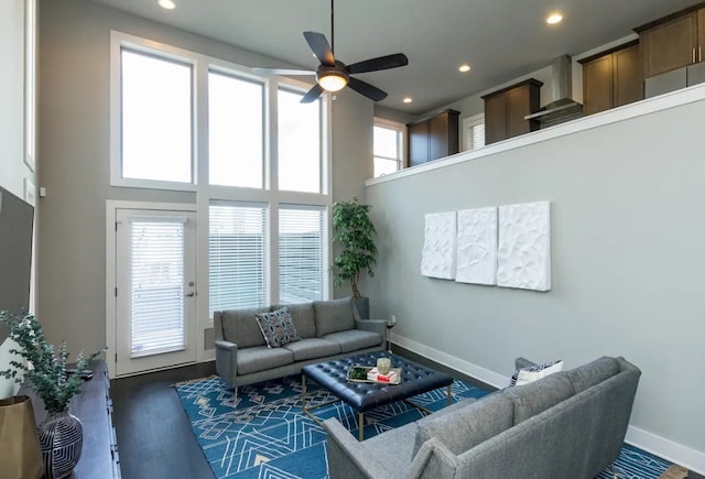 living room with plenty of natural light, dark hardwood / wood-style flooring, ceiling fan, and a high ceiling