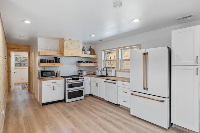 kitchen featuring white appliances, white cabinetry, sink, and light hardwood / wood-style flooring