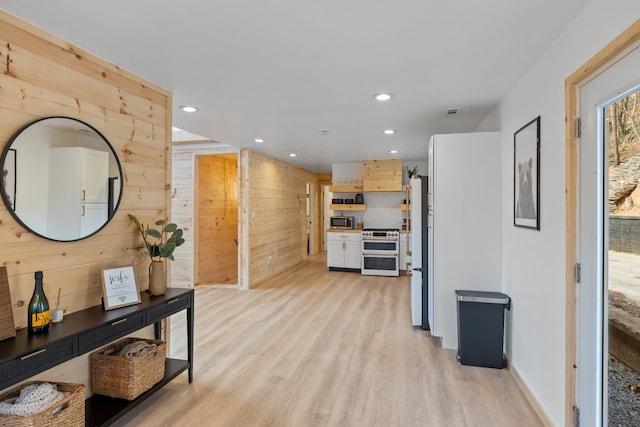 corridor featuring light hardwood / wood-style floors and wood walls