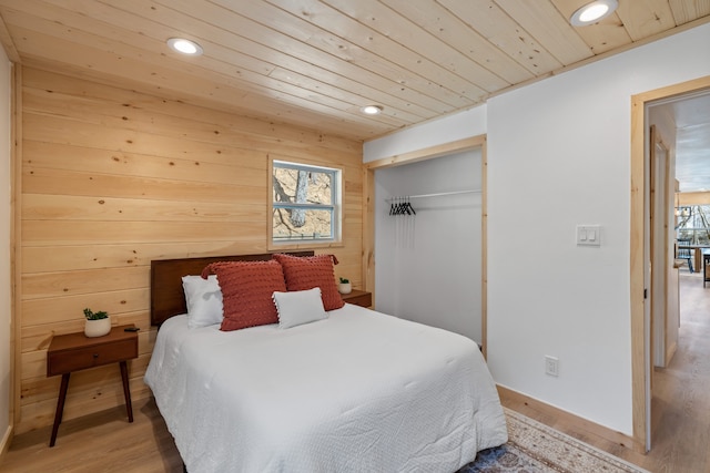 bedroom with light hardwood / wood-style flooring, wood ceiling, and a closet