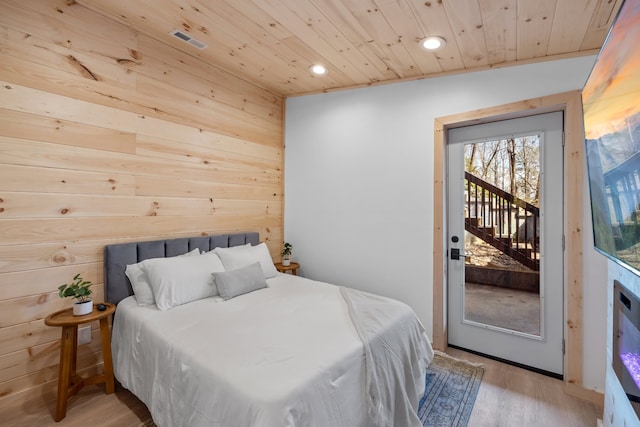 bedroom with wooden walls, light hardwood / wood-style flooring, wood ceiling, and access to exterior