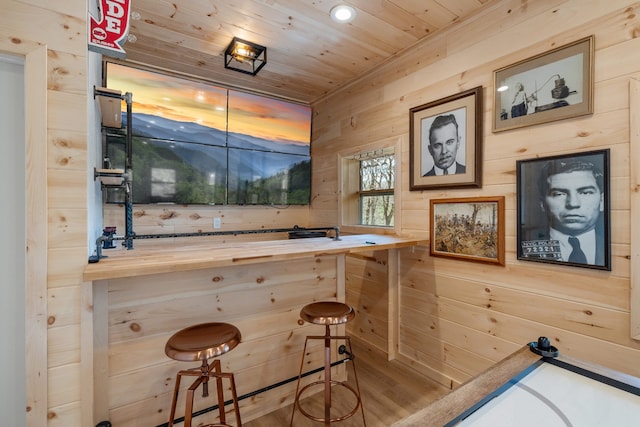 bar with butcher block countertops, wooden ceiling, wood walls, and hardwood / wood-style flooring