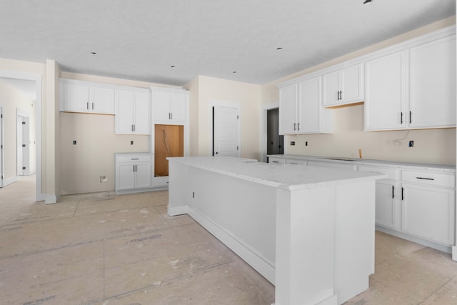 kitchen featuring white cabinets, light stone counters, and a kitchen island