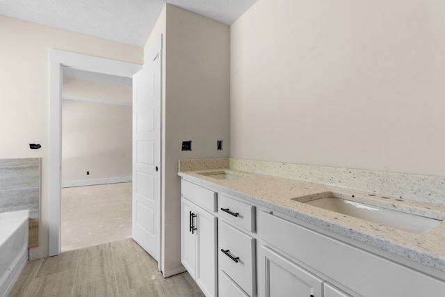 bathroom featuring vanity, a bathtub, and a textured ceiling