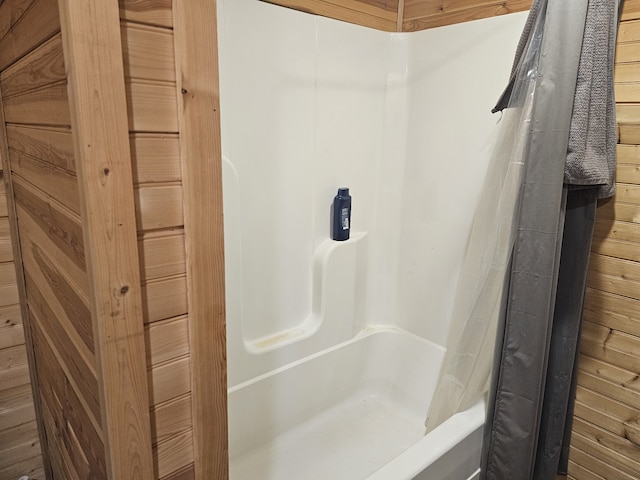 bathroom featuring wooden walls and shower / bath combination with curtain