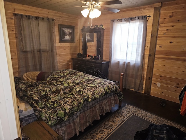 bedroom with ceiling fan and wood walls