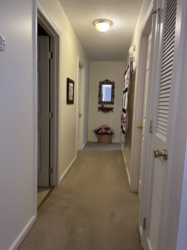 corridor featuring light carpet and a textured ceiling