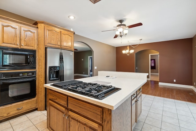 kitchen featuring hanging light fixtures, ceiling fan with notable chandelier, black appliances, light wood-type flooring, and a kitchen island