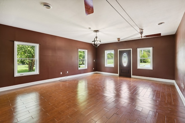 spare room with an inviting chandelier, dark parquet floors, and a wealth of natural light