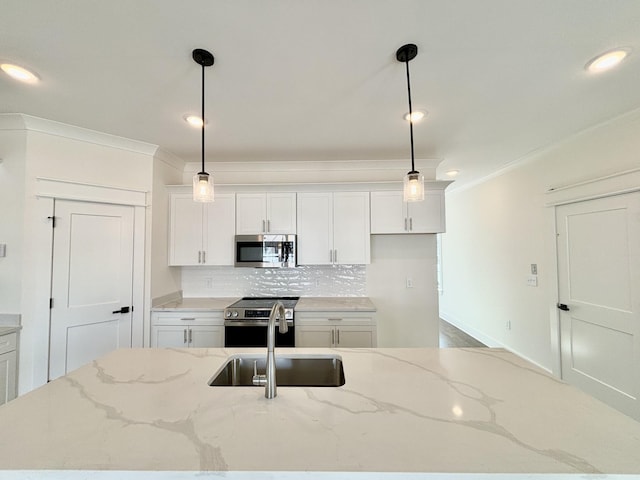 kitchen featuring stainless steel appliances, a sink, white cabinetry, ornamental molding, and backsplash