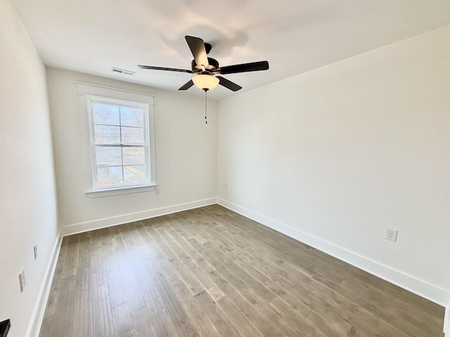 spare room featuring visible vents, baseboards, and wood finished floors