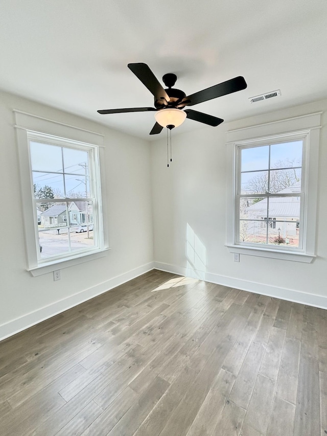 spare room featuring baseboards, visible vents, and wood finished floors