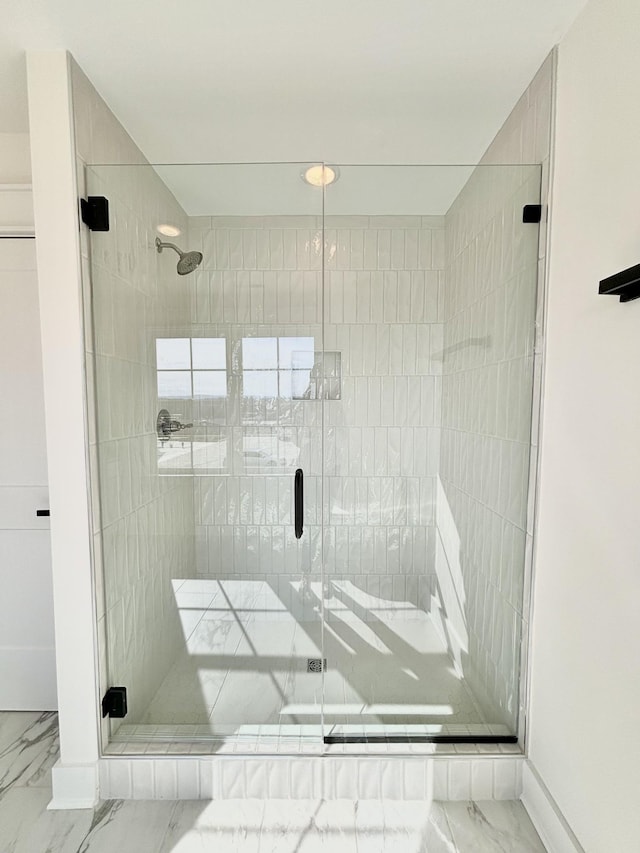 bathroom with marble finish floor and a shower stall