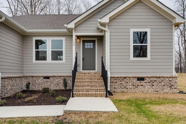 doorway to property featuring crawl space, brick siding, and roof with shingles