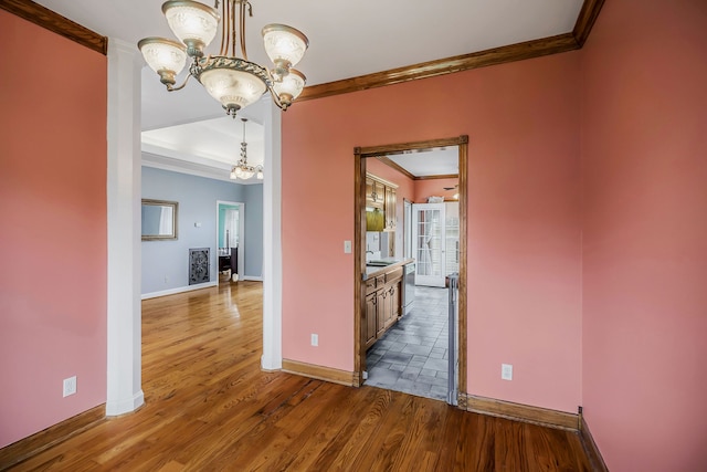 empty room featuring ornamental molding, an inviting chandelier, dark hardwood / wood-style floors, and sink