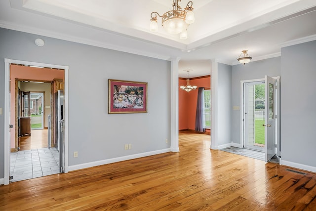 tiled spare room featuring a raised ceiling, an inviting chandelier, and ornamental molding