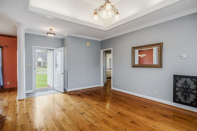 empty room featuring an inviting chandelier, crown molding, and light wood-type flooring