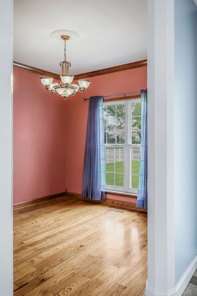 unfurnished room featuring light hardwood / wood-style flooring, a notable chandelier, and ornamental molding