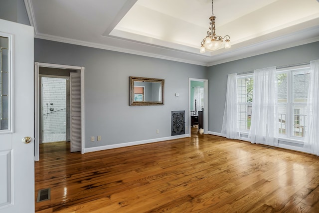 unfurnished living room featuring a chandelier, a tray ceiling, and light wood-type flooring