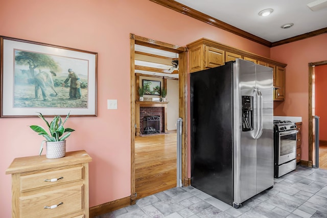 kitchen with appliances with stainless steel finishes, light tile flooring, crown molding, and a brick fireplace